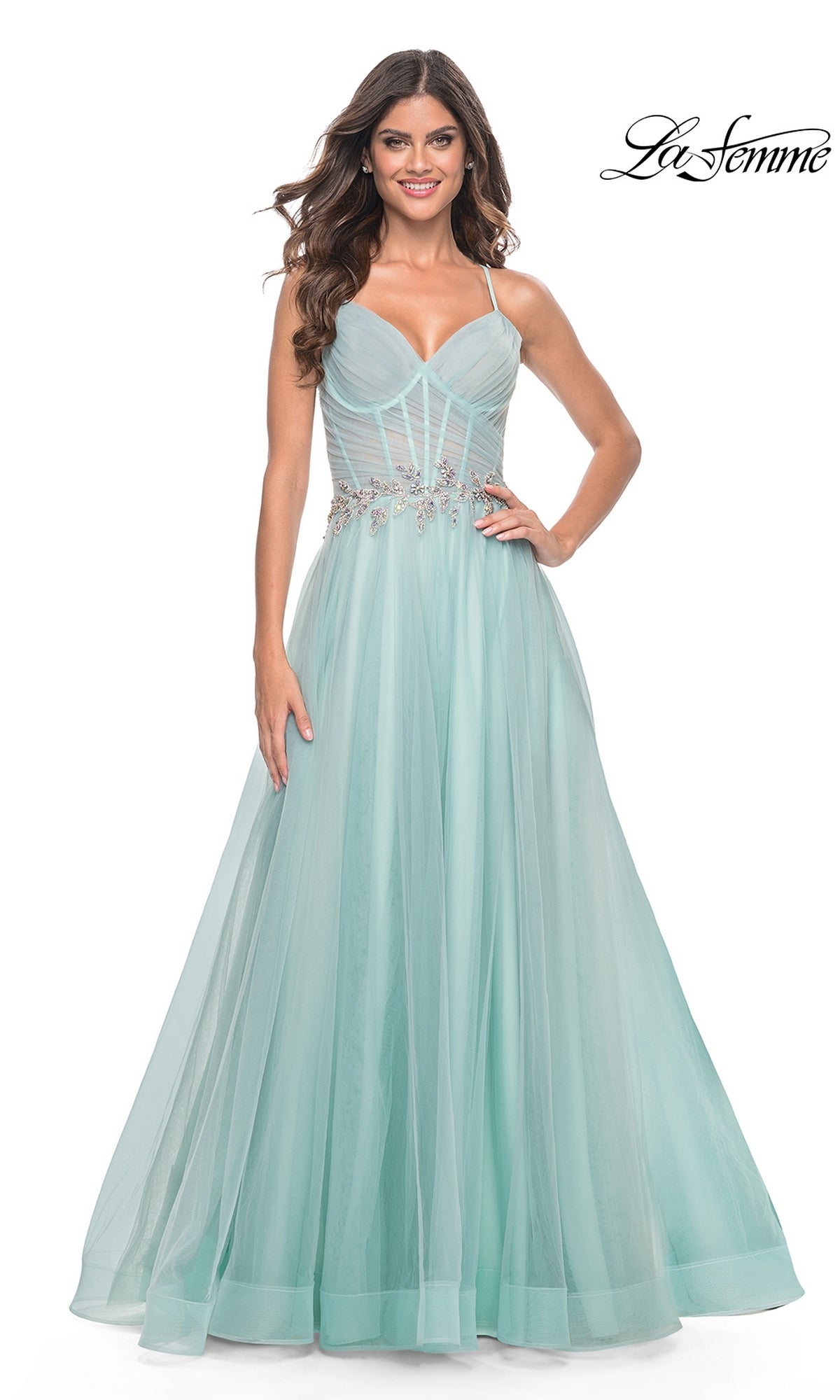 A woman wears the La Femme Sheer-Bodice Long A-Line Prom Dress 32117, a light blue, floor-length gown with thin straps, a fitted bodice, beaded waist detail, and a strappy open-back for an elegant modern look.
